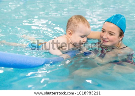 Swimming coach teaches the child to swim in the pool