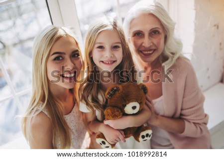 Little cute girl, her attractive young mother and charming grandmother are spending time together at home. Women's generation. International Women's Day. Happy Mother's Day.
