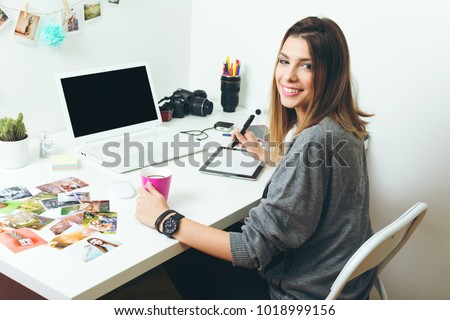 Young freelance female photographer at home, working on laptop in home office