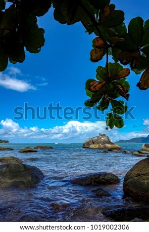 View of Juliao beach in Ilhabela - Sao Paulo, Brazil -  with rocks in the sea on sunny day with blue sky with clouds