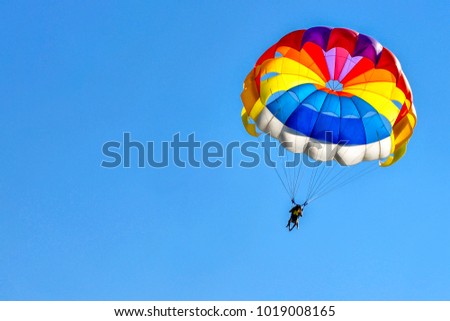 Two men are gliding using a parachute on the background of the blue sky. Royalty-Free Stock Photo #1019008165