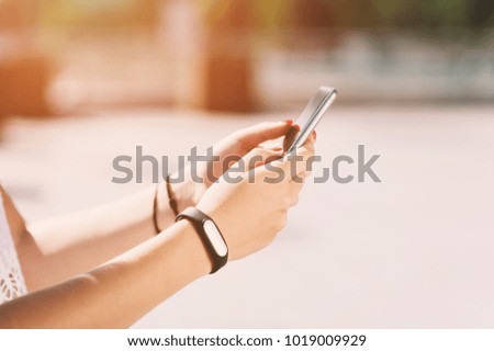 Close-up girl holding mobile smartphone the hands on sunset background, soft focus