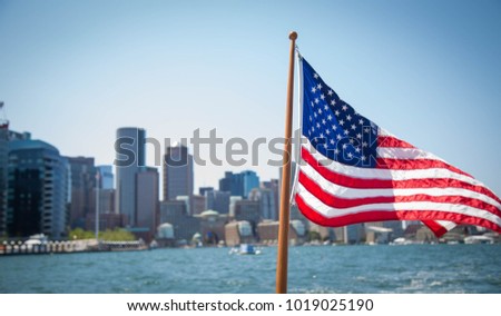 American flag flying with Boston in the background.