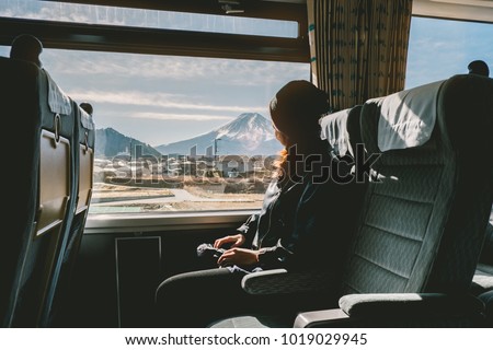 Enjoying travel. Young pretty woman traveling by the train from sitting near the window and looking mountain Fuji. vintage filter. Travel concept Royalty-Free Stock Photo #1019029945