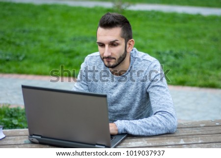 Hipster guy working on laptop outside