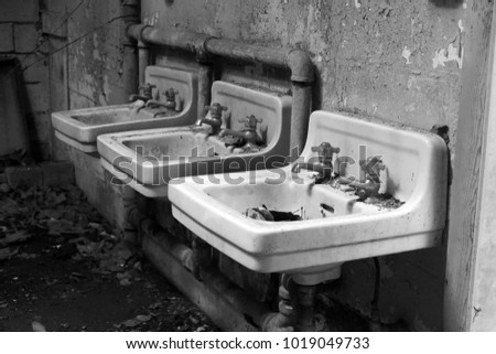 Black and white image of sinks in an abandoned building.                                