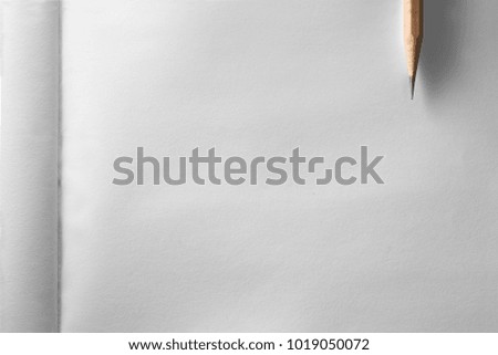 Minimalist template with copy space by top view close up macro photo of wooden pencil isolated in texture white paper of notebook by flash light to show paper texture and smooth shadow from pencil.