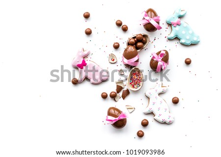 Sweets for Easter table. Chocolate eggs near cookies in shape of Easter bunny on white background top view copy space Royalty-Free Stock Photo #1019093986
