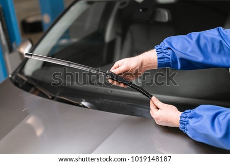 Technician is changing windscreen wipers on a car station. Royalty-Free Stock Photo #1019148187