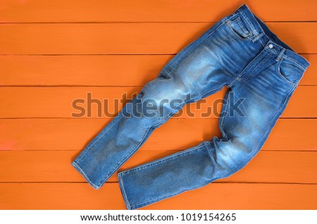 Blue mens jeans denim pants on orange background. Contrast saturated color. Fashion clothing concept. View from above Royalty-Free Stock Photo #1019154265