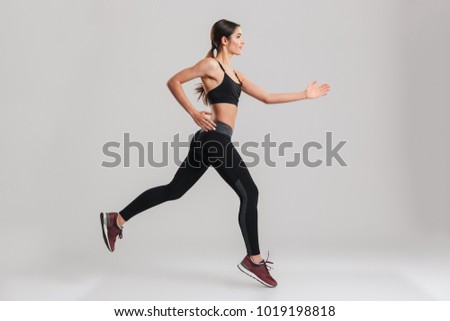 Profile picture of energetic caucasian female in sportswear running isolated along gray background