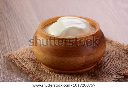 cream sour in a wooden plate on table