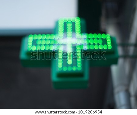 Blurred image of the green medical cross of the pharmacy symbol. Background picture with space for text.