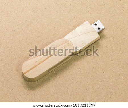 Flash drive on brown cardboard texture background.  USB stick made from wood material concept.