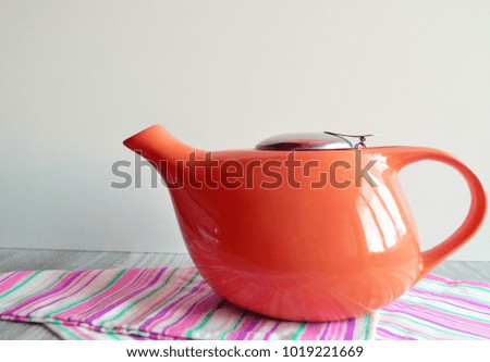 Close-up red teapot on striped napkin. White background.