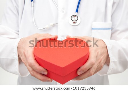 Doctor with a closed red gift box with heart shape in his hands.