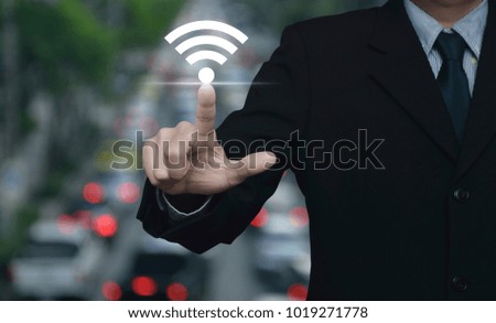 Businessman pointing to wi-fi button over blur of rush hour with cars and road, Technology and internet concept