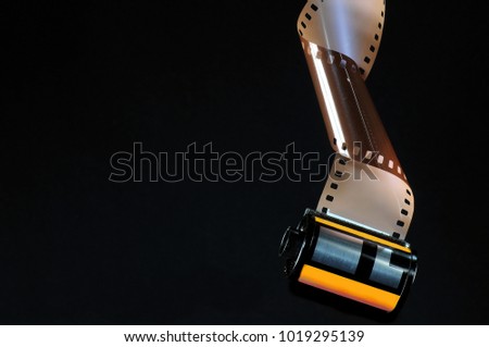 Roll of rolled-up photographic film on a black background.