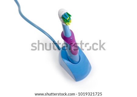 Top view of the blue electric toothbrush with rotating and oscillating brushes in the contactless inductive charging base closeup at selective focus on a white background
