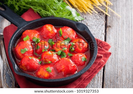 Meatballs in tomato sauce in a cast-iron frying pan on a wooden table, horizontal, copy space