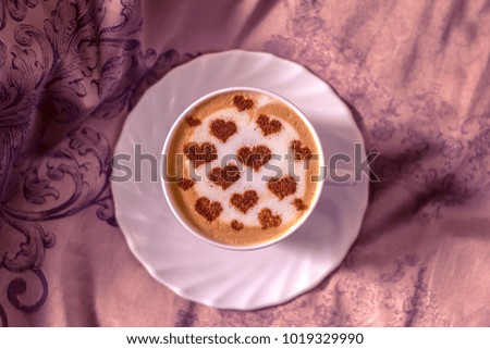 coffee in a white cup with a pattern of heart from cinnamon on milk foam