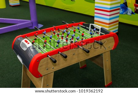 Green wooden table football in the children room. Foosball in children centre with colorful walls on background. Play entertainment centre.