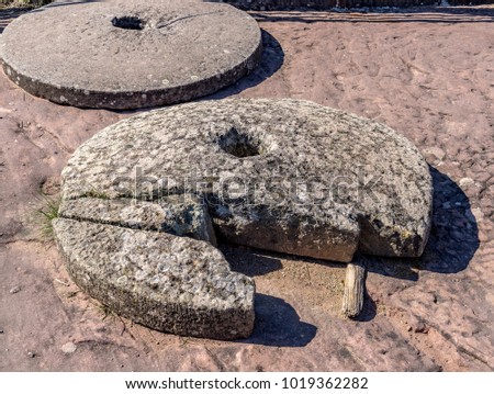 Broken medieval millstones lying on the ground in the sunlight