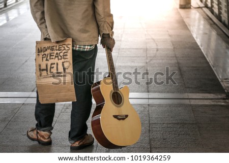 homeless or beggar of a poor and dirty man walking on walkway to somewhere in urban and text please help on cardboard