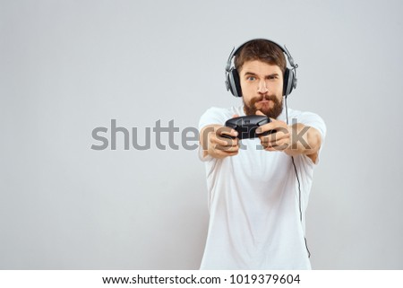   man with a beard with headphones in his hand joystick on a light background                             