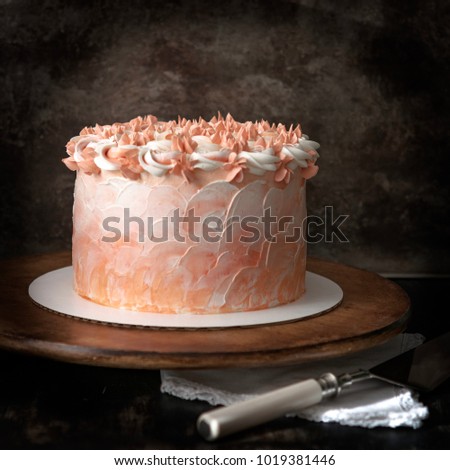 Tasty cake with orange frosting on a wooden stand and cake cutter. Brown background.Birthday concept. Mothers day.
