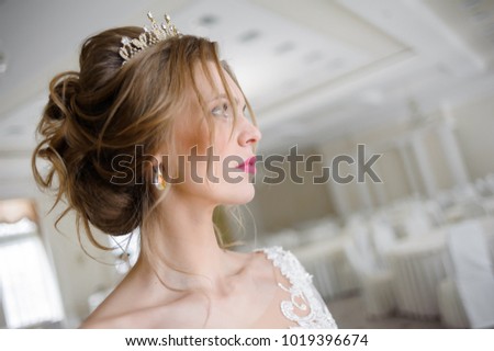 Beautiful bride in a wedding dress in white interior