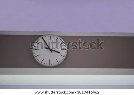 Soft focus of white clock on soft colorful wooden wall in office or inside house, use for your background, pattern, design or your concept. Clock is mechanical or electrical device for measuring time.