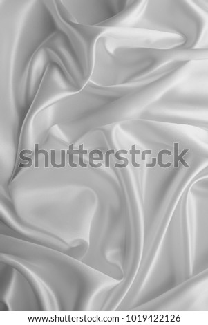 Smooth elegant wavy white silk or satin luxury cloth fabric texture, abstract background design.