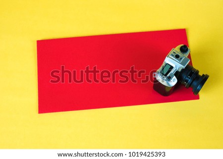 Mini camera toy and red envelop on yellow background with copy space for add text.