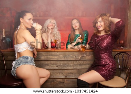 beautiful girls at a bachelorette party in a red smoky bar drinking alcohol and having fun