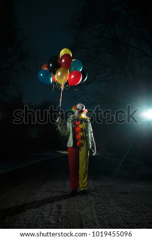 Photo of clown with balls in hands at night