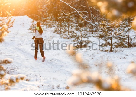Photo from back of athlete running through winter forest