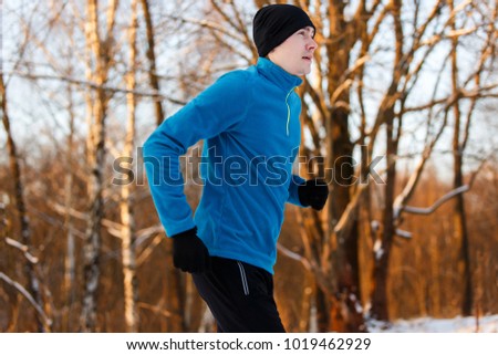 Photo of young athlete running through winter forest