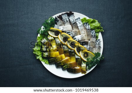 on fabric dark background on a plate beautiful herring and mackerel