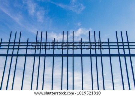 blue sky behind the bars of a fence