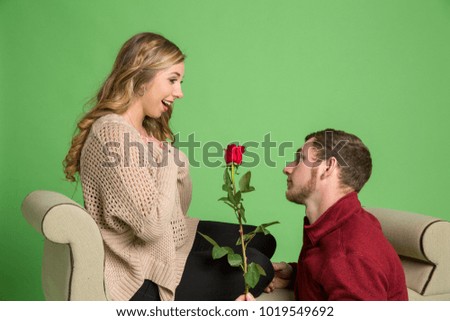 Attractive young couple posing in studio. Laughing smiling. She has red roses.
