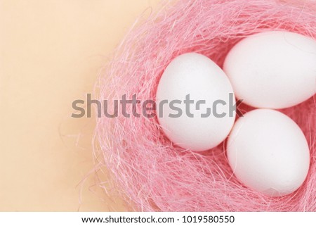 Easter white eggs in pastel pink nest on yellow background. Close up in minimalism style.