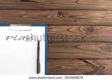 the plan is written on a piece of paper with a fountain pen. on a wooden background.
