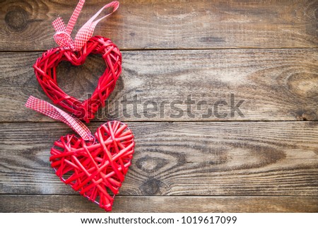 red wicker heart with ribbon on a wooden background