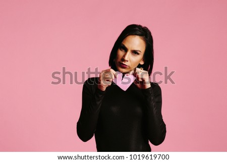 woman in black ripping, holding a broken pink heart