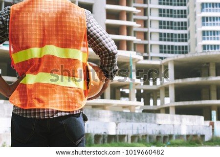 Rear view of engineer in safety vest ready to work on construction site