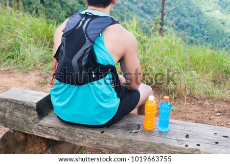 Trail runner sitting with bottle of energy drink and orange juice.
