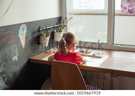 Little girl in a red and blue dress sculpts from plasticine, children's room with a slate wall, pencils and plasticine, children's creativity, a chair and a table for classes, kids craft, cartoon.