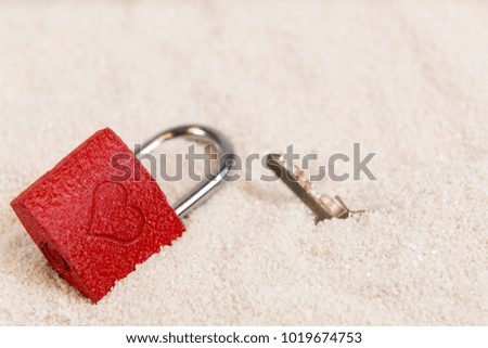 Red love padlock on the white beach