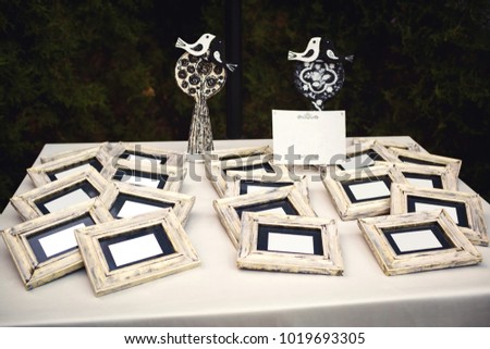 white sheets of paper in wooden photo frames lie on the table, and behind there is a bird's decoration kissing. Decor in pastel colors. Mockup.